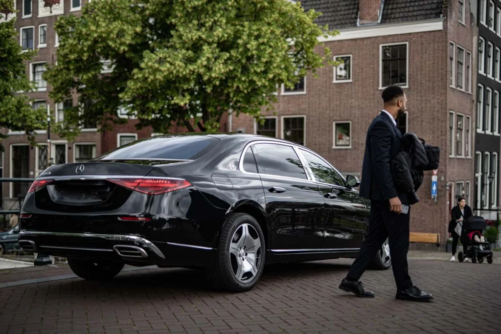 A private driver in the canals of amsterdam with a mercedes maybach. They are standing on top of a bridge. Golf match transfer