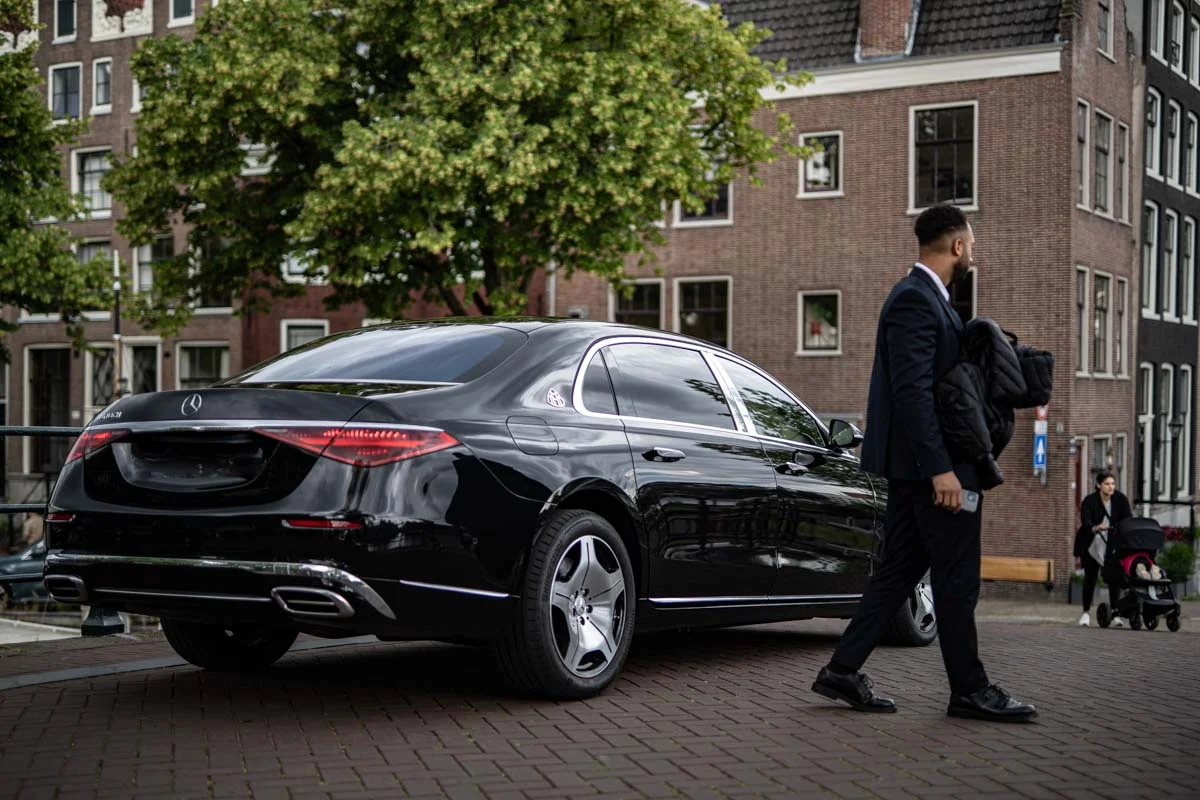 A private driver in the canals of amsterdam with a mercedes maybach. They are standing on top of a bridge.